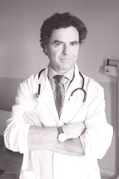 Il prof. Samir Giuseppe Sukkar, in piedi in una stanza d'ospedale, con il camice e lo stetoscopio attorno al collo.